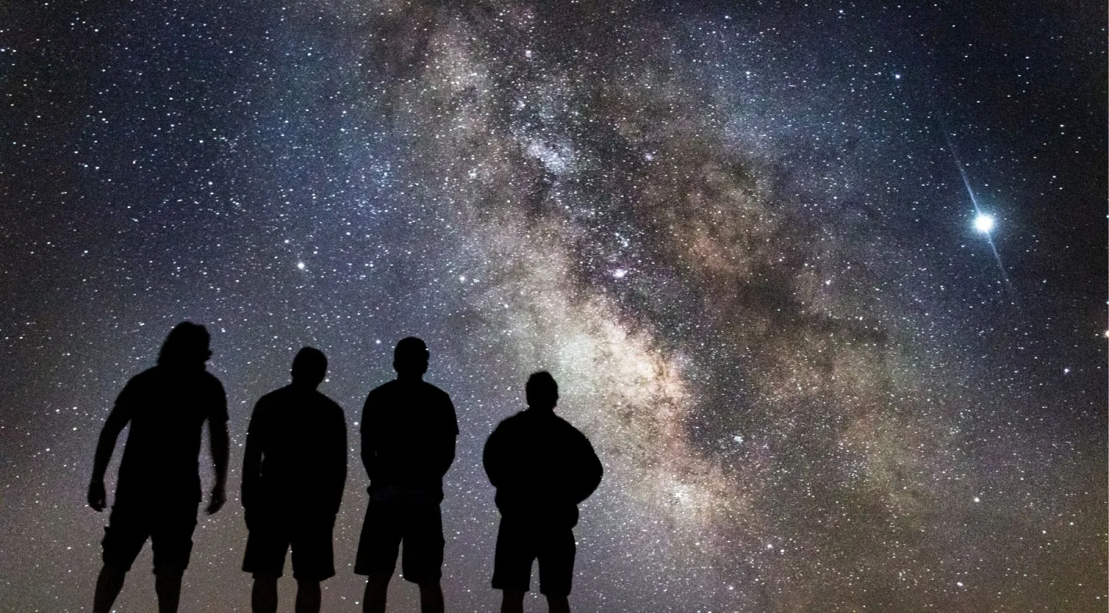Four stargazers silhouetted against the Milky Way over Teide National Park