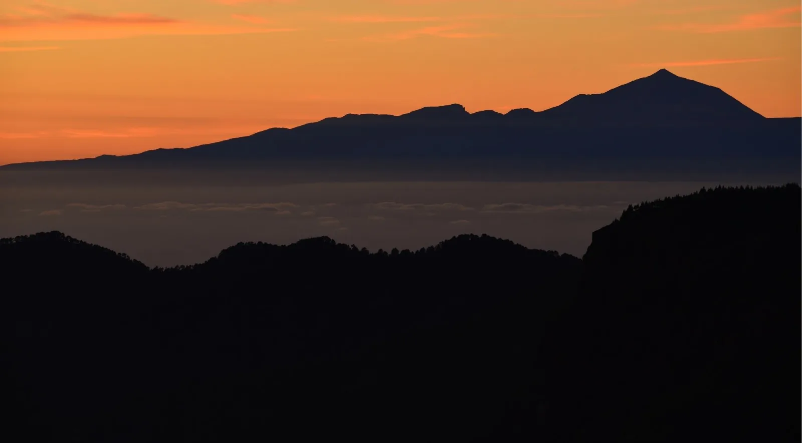 The Teide ridge in silhouette against a deep orange post-sunset sky