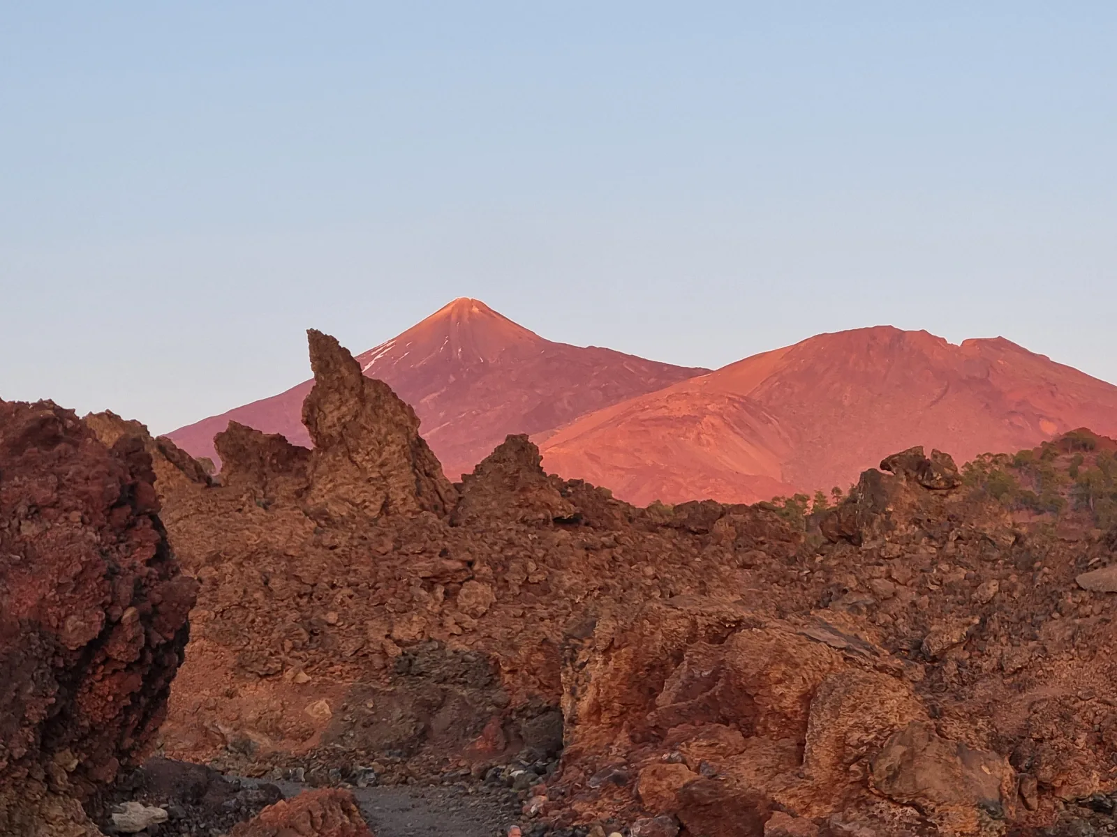 Teide's summit cone lit pink at sunset above the lava rocks of the caldera