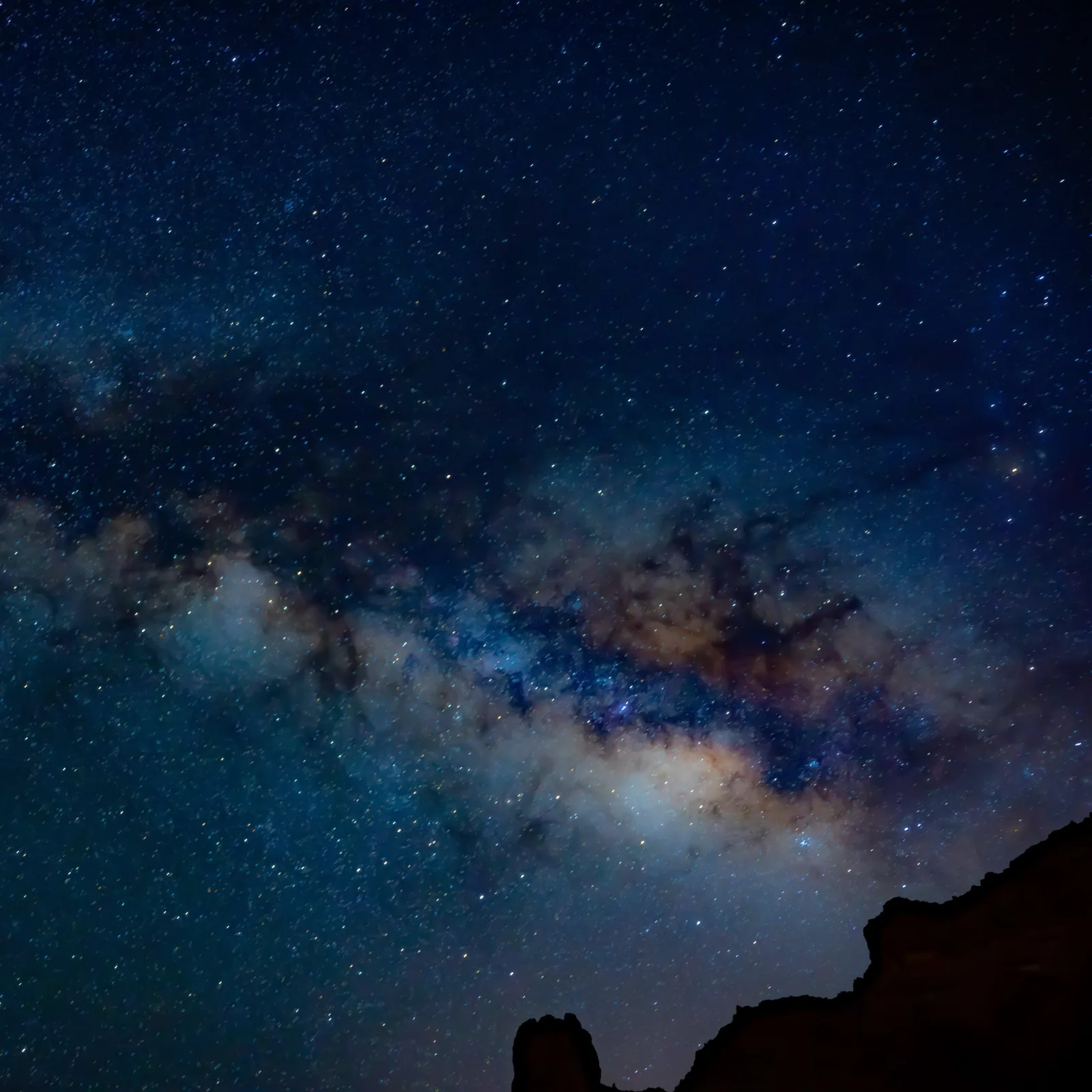 The core of the Milky Way arching across a deep blue star field