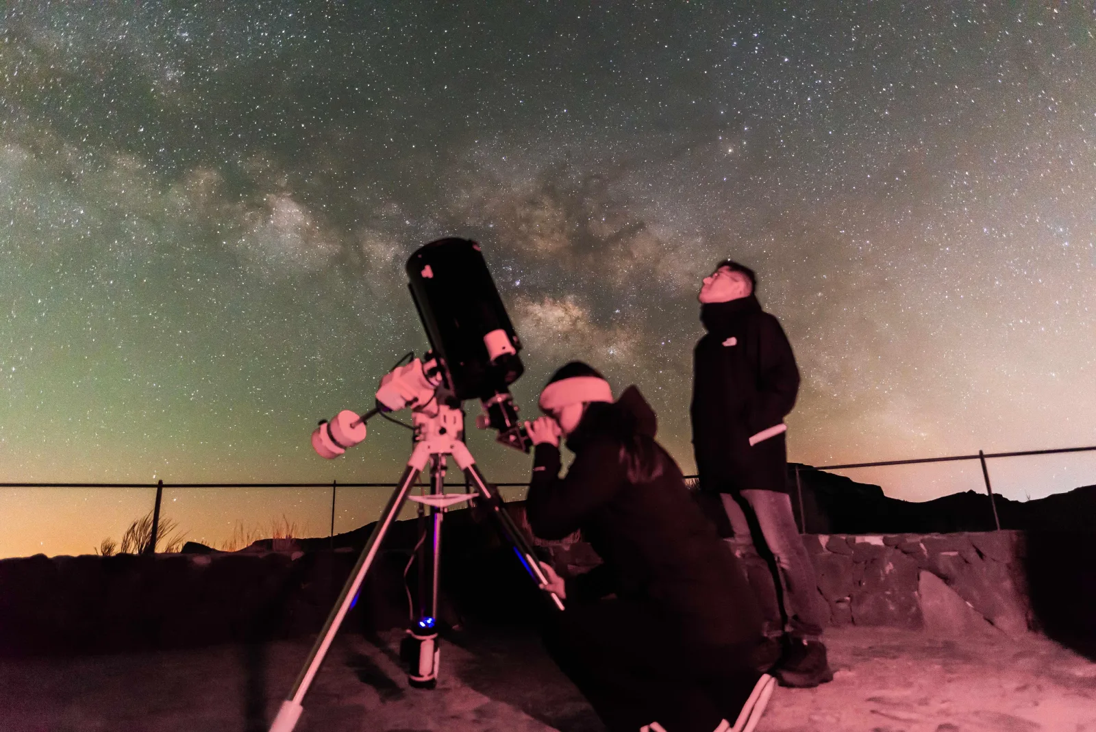 Guests at the eyepiece with the Milky Way overhead at a park viewpoint