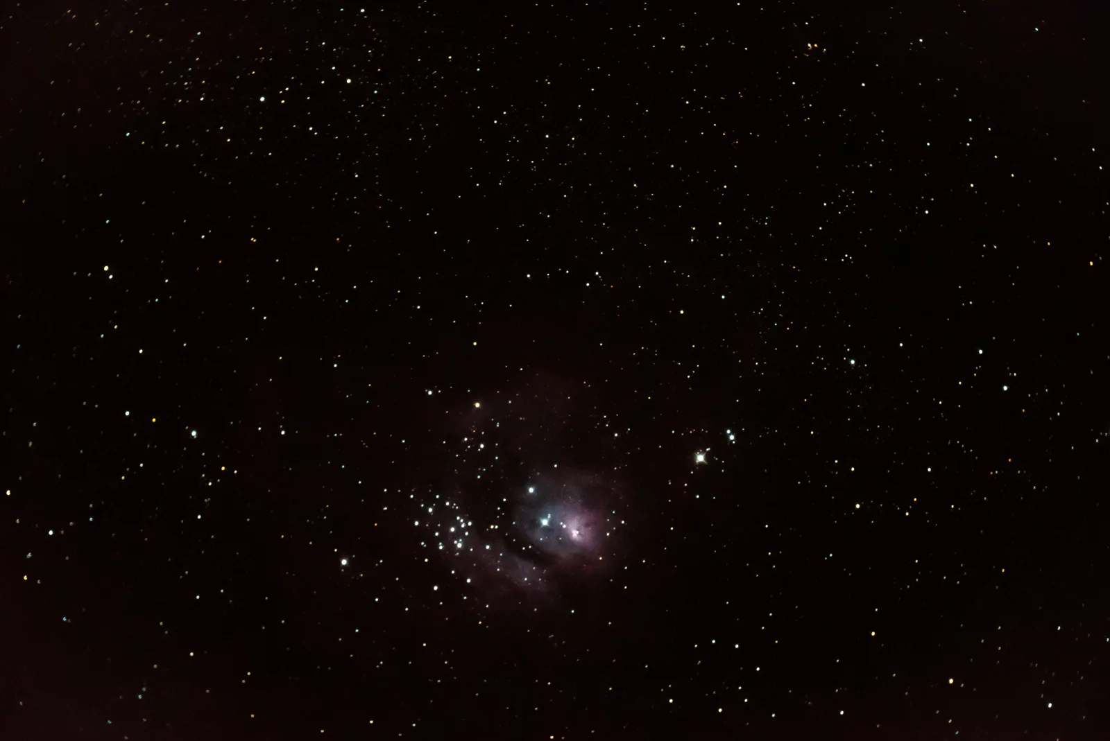 A star field with a faint nebula low in the frame