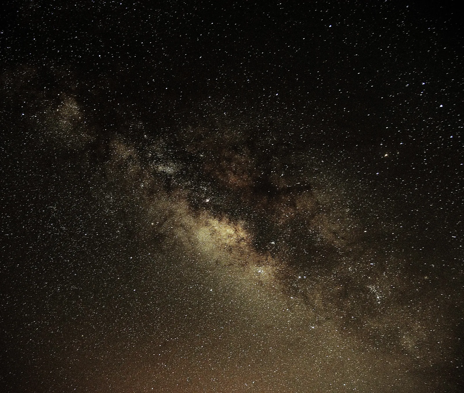 The Milky Way's core above the dark ridgeline of the caldera
